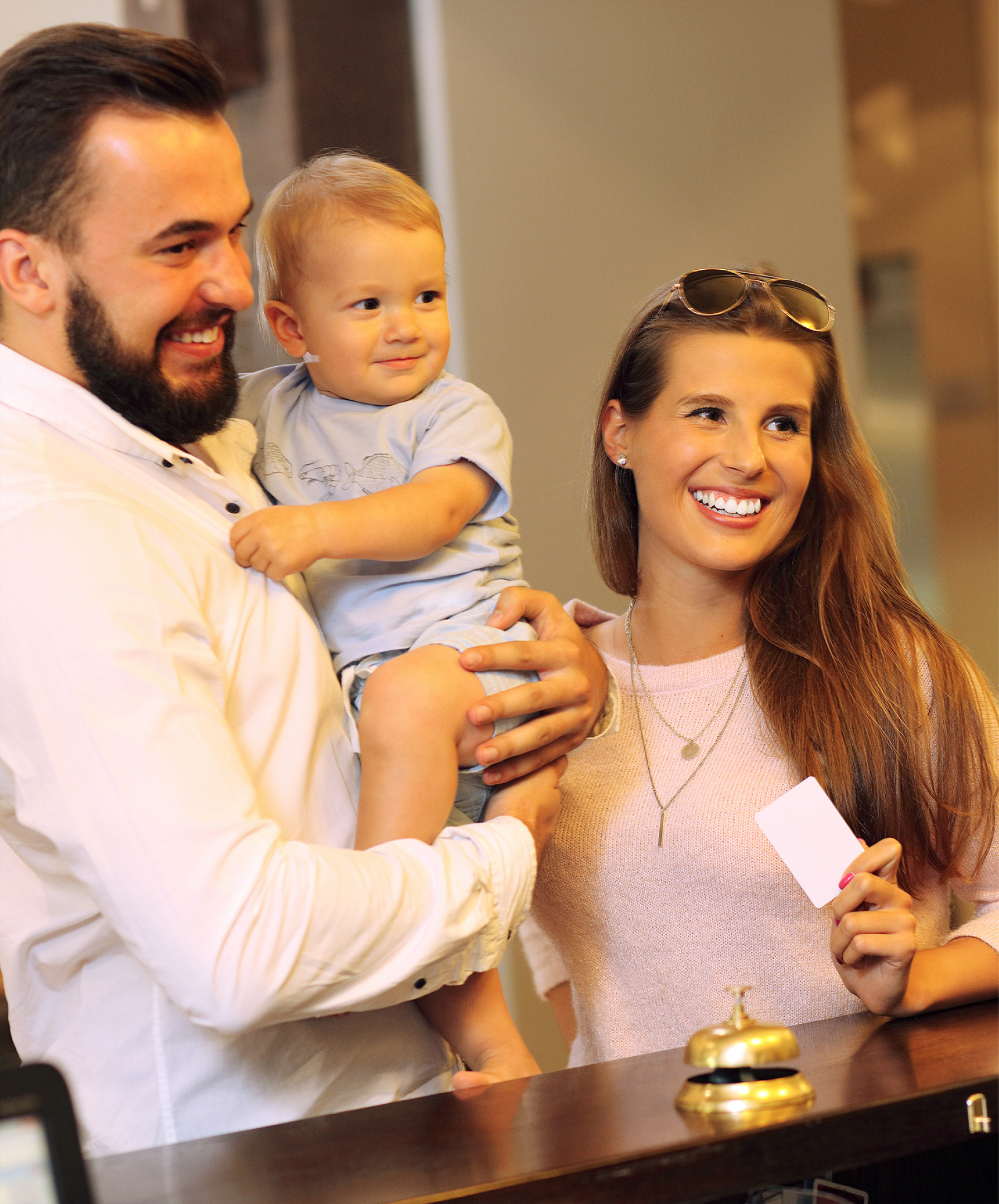 happy couple with baby checking into a hotel